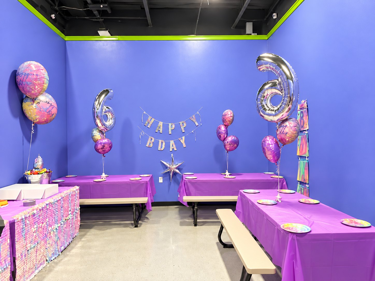Nova party room decorated with silver number balloons, a Happy Bday banner and purple party tables